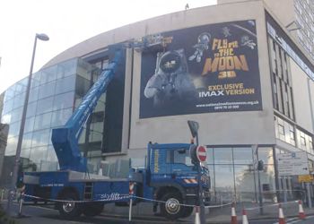 Promotional banner installation by crane attached to lorry.