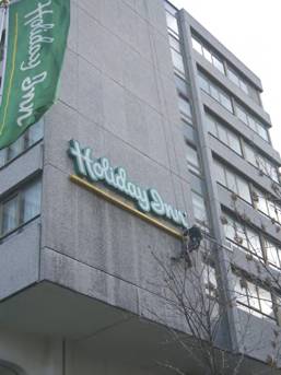 Only three storeys up, this is relatively low level work for Special Abseiling Services. Man abseiling down a building to work on a sign