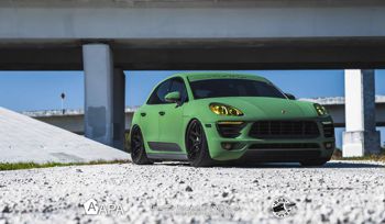 Green car parked under bridge