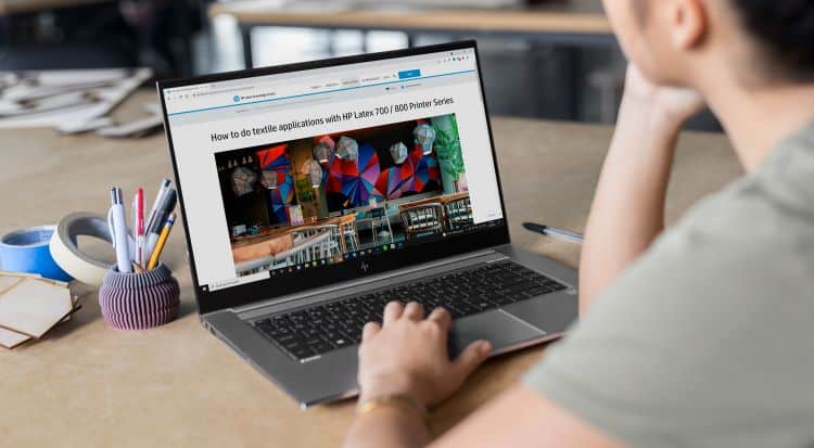 Man accessing the HP Latex Knowledge Center via a laptop computer