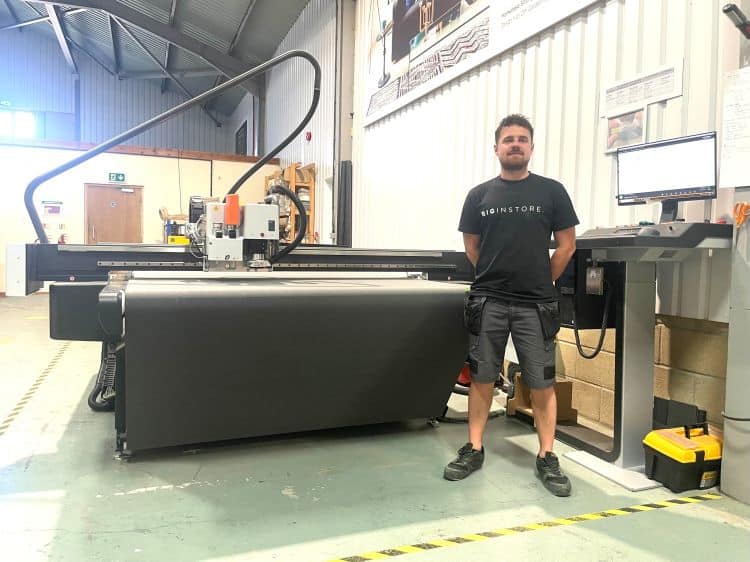 A man stands in a large workshop in front of a new digital cutting table